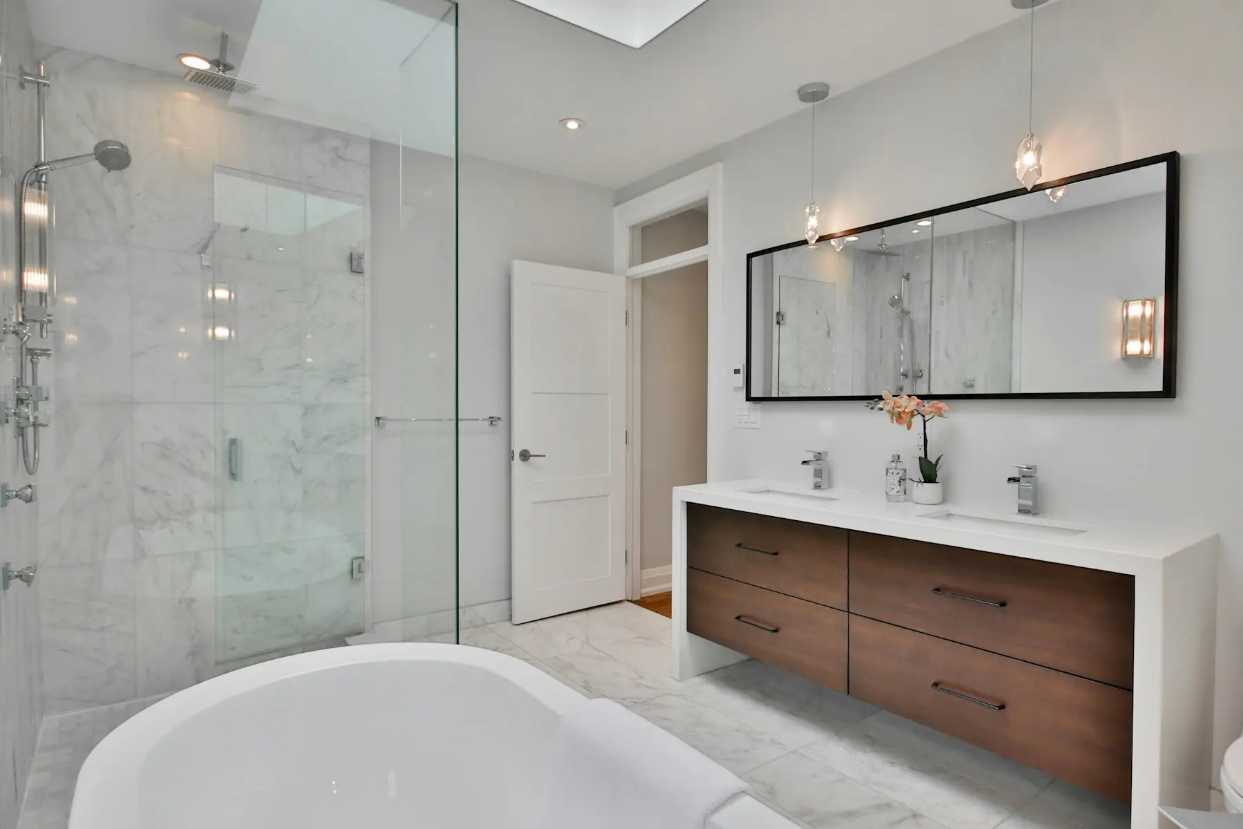 Floating walnut double vanity and backlit mirror