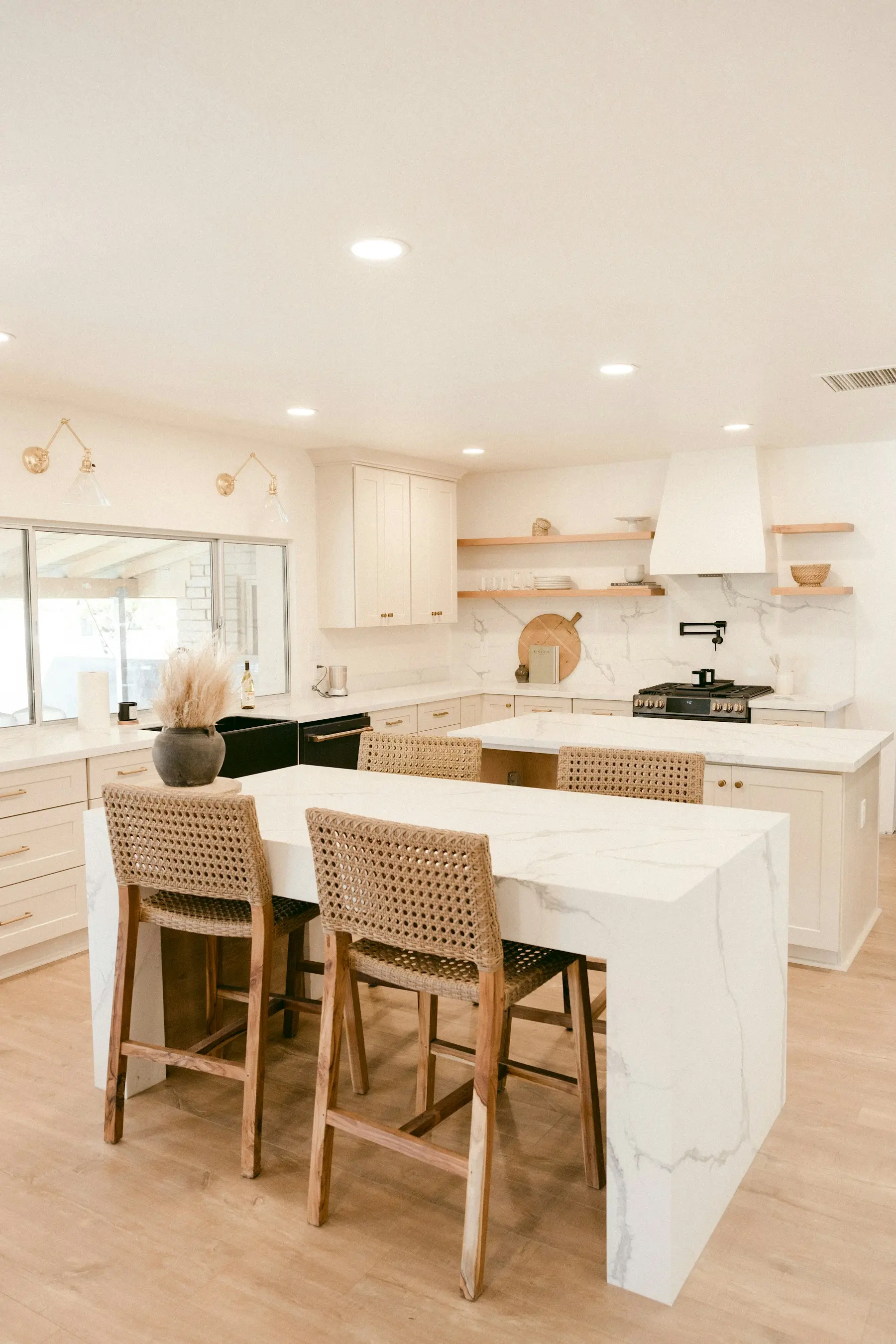 White kitchen with marble-look quartz island and woven counter stools